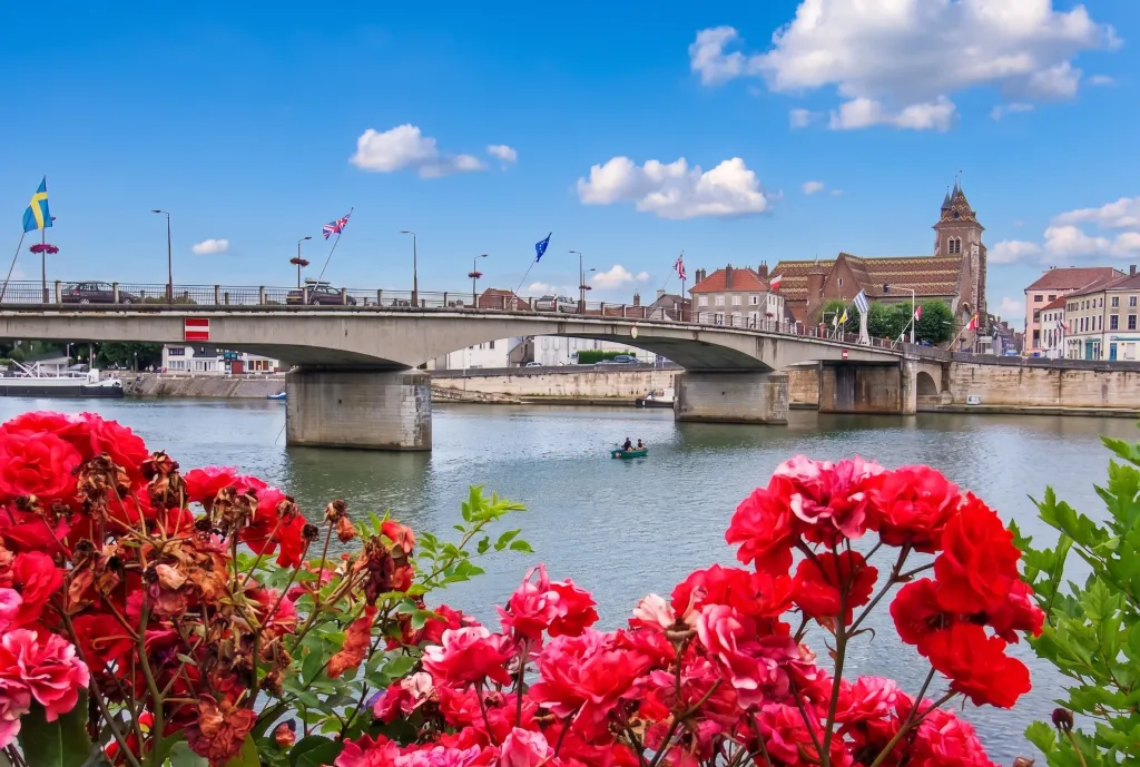 Pont Legay sur l'Yonne à Joigny avec fleurs rouges au premier plan.